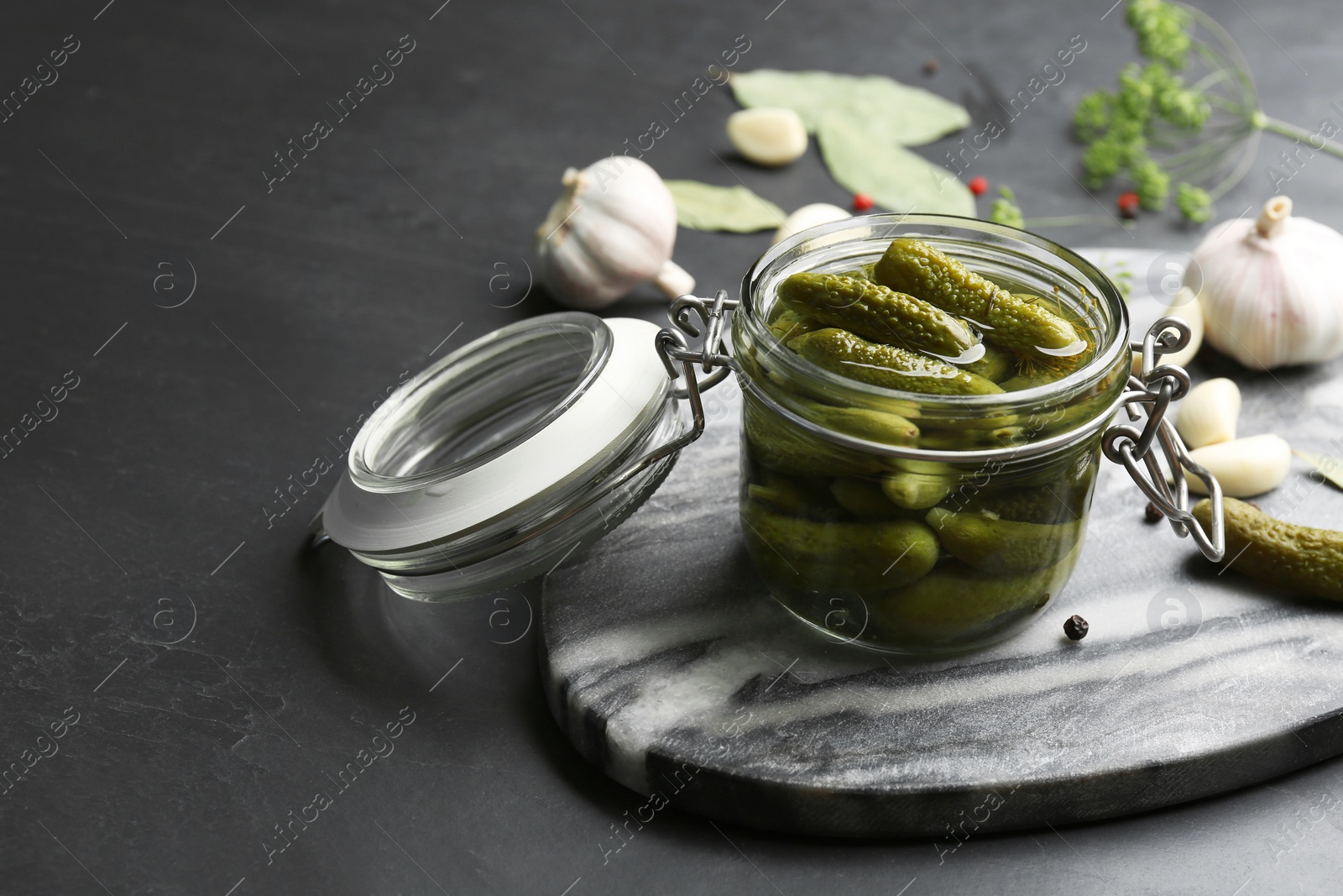 Photo of Glass jar of pickled cucumbers on black table. Space for text