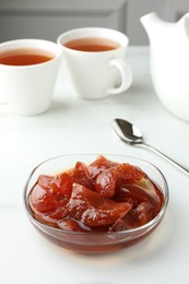 Quince jam in glass bowl served to tea on white table