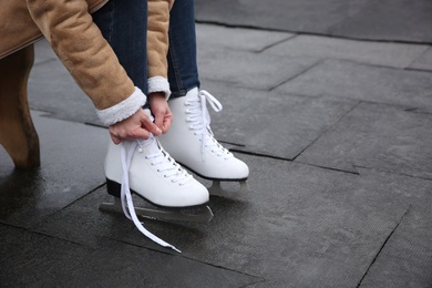 Photo of Woman lacing figure skate outdoors, closeup. Space for text