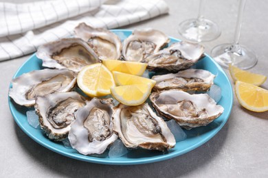 Fresh oysters with lemon on grey table, closeup