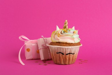 Cute sweet unicorn cupcake and gift boxes on pink background