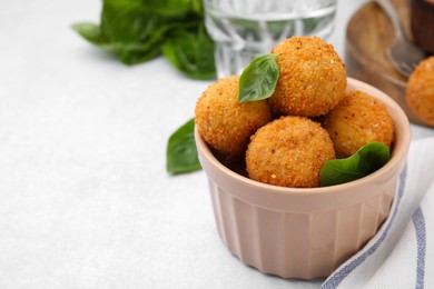 Photo of Bowl of delicious fried tofu balls with basil on white table, space for text