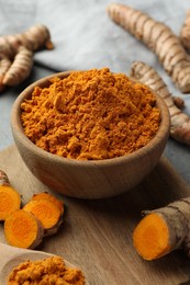 Photo of Aromatic turmeric powder and cut roots on grey table