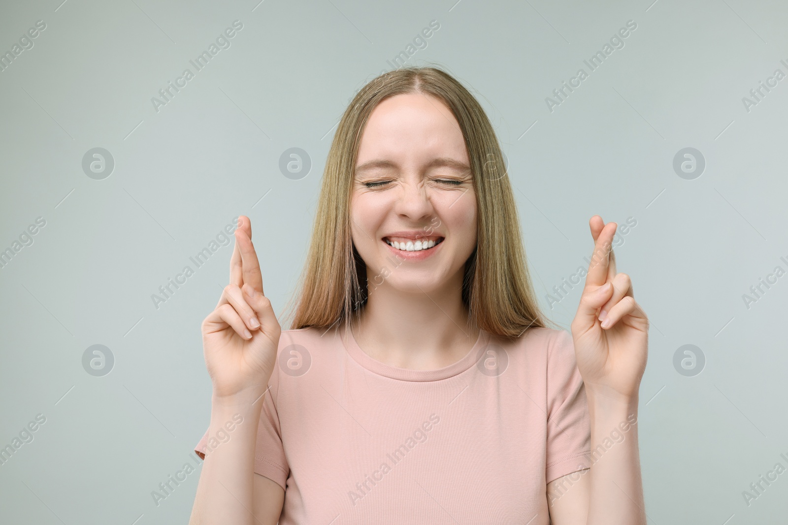 Photo of Woman crossing her fingers on grey background