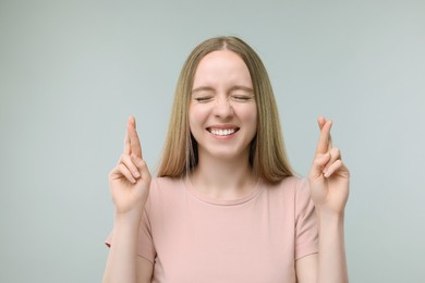 Woman crossing her fingers on grey background
