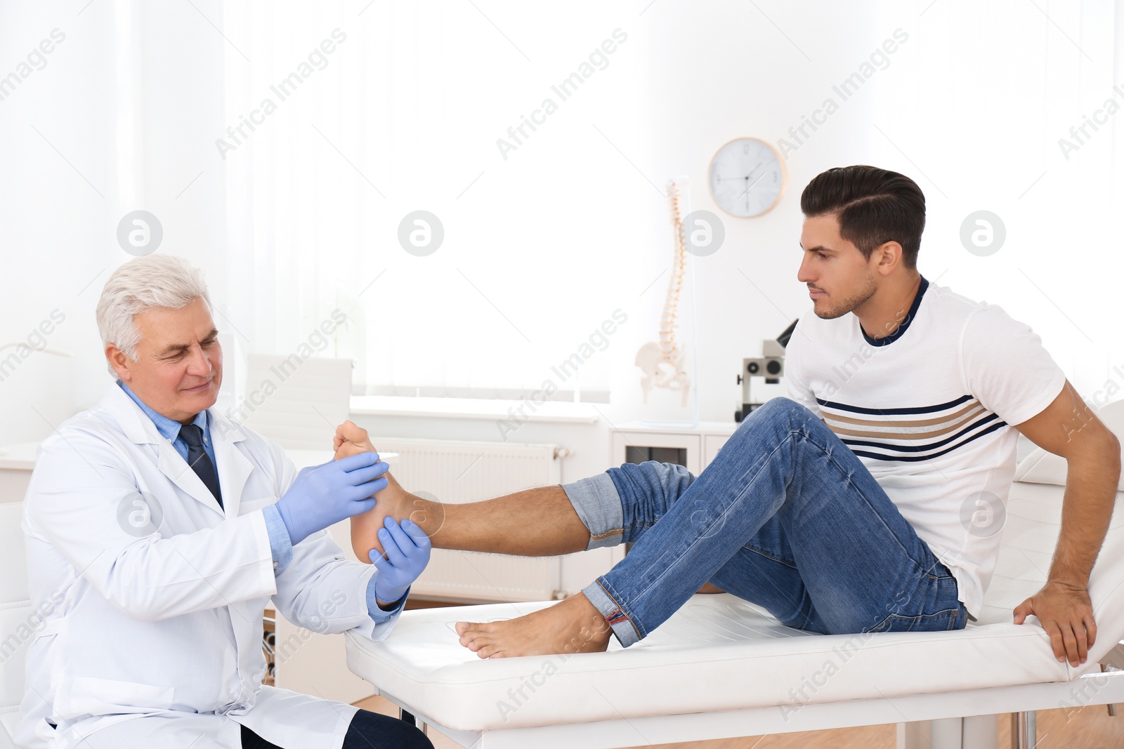 Photo of Male orthopedist checking patient's foot in clinic