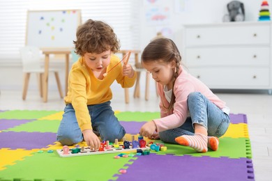 Cute little children playing with math game Fishing for Numbers on puzzle mat in kindergarten