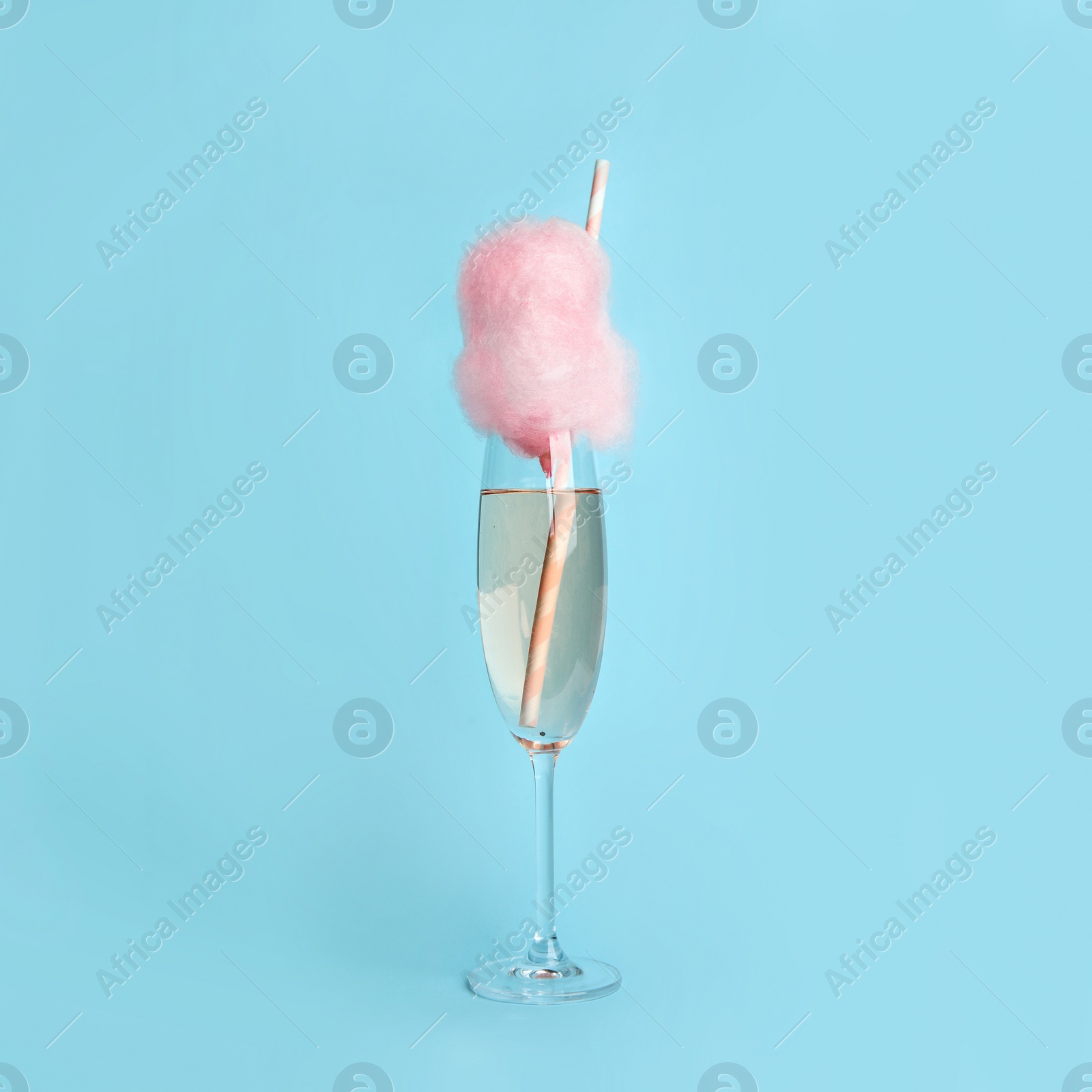 Photo of Cocktail with cotton candy in glass on light blue background