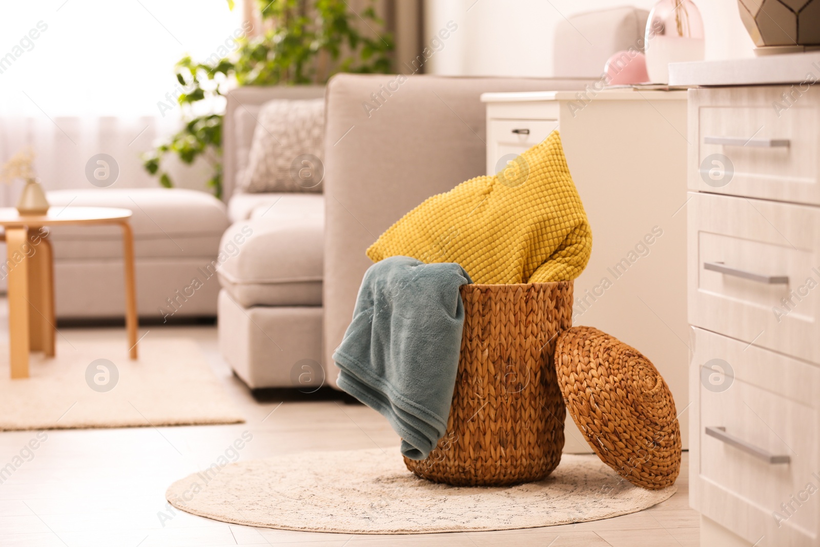 Photo of Basket with blanket and pillow in light room