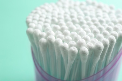 Plastic container with cotton swabs on color background, closeup