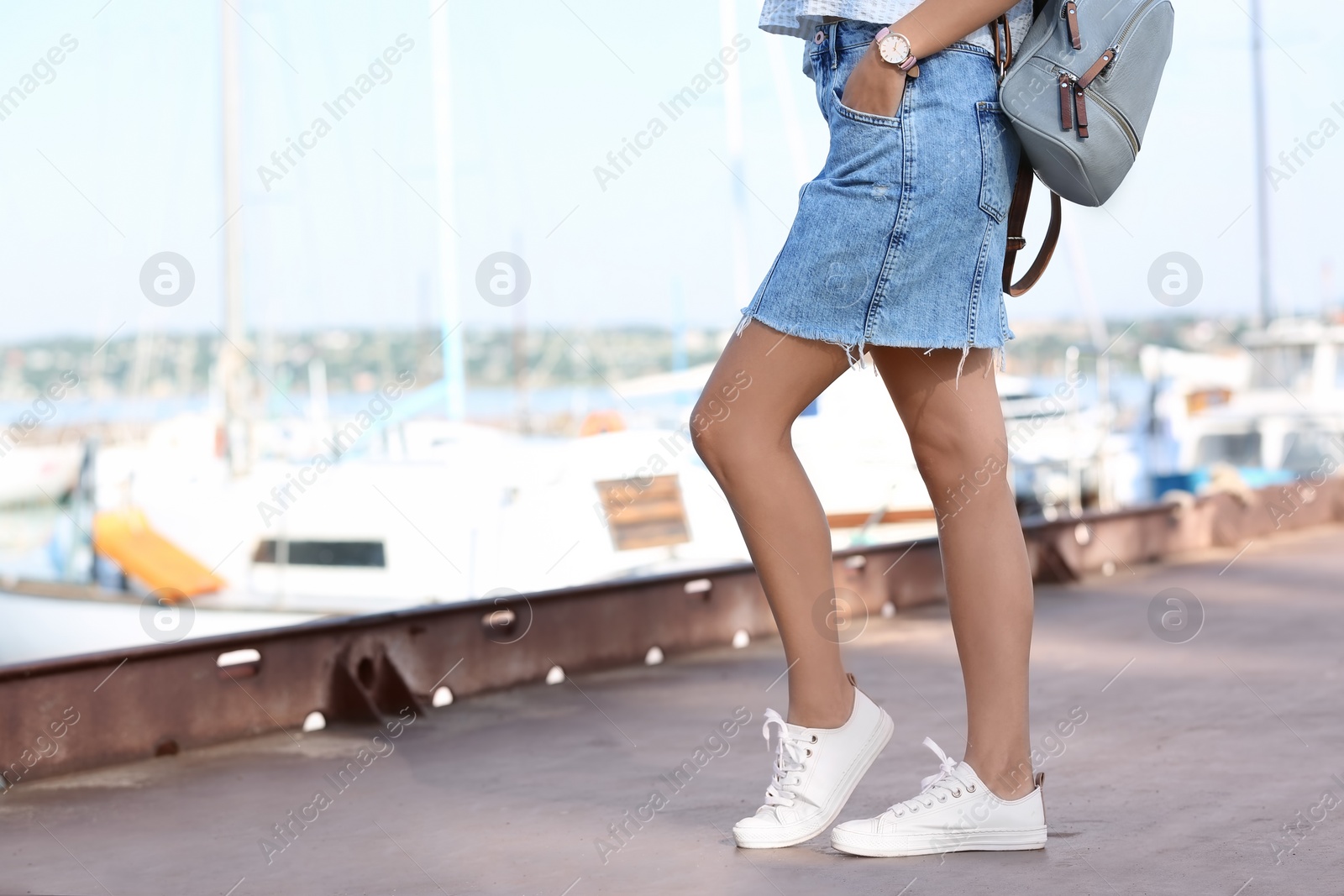 Photo of Young hipster woman in jean skirt on pier