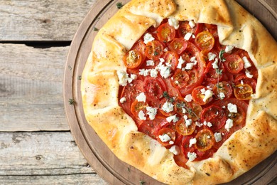 Photo of Tasty galette with tomato, thyme and cheese (Caprese galette) on wooden table, top view. Space for text