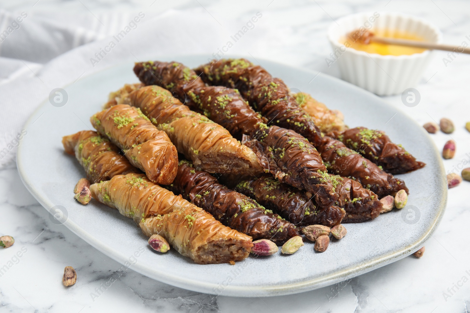 Photo of Delicious baklava with pistachio nuts on white marble table