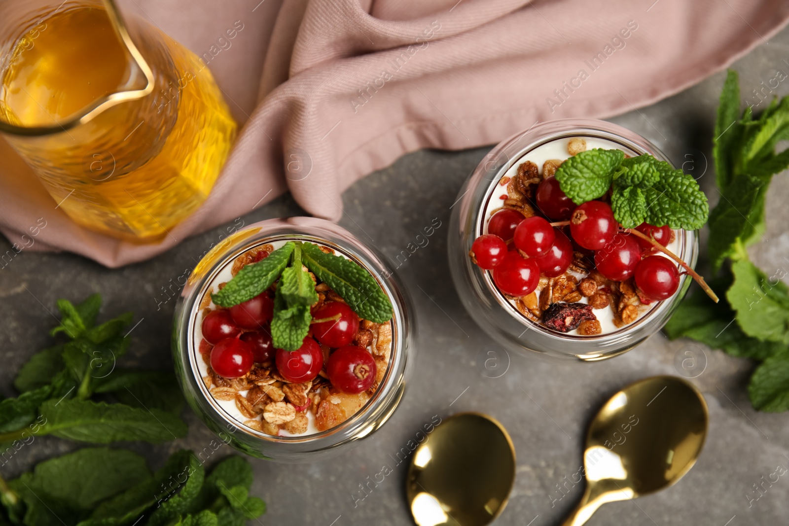 Photo of Delicious yogurt parfait with fresh red currants and mint on grey table, flat lay
