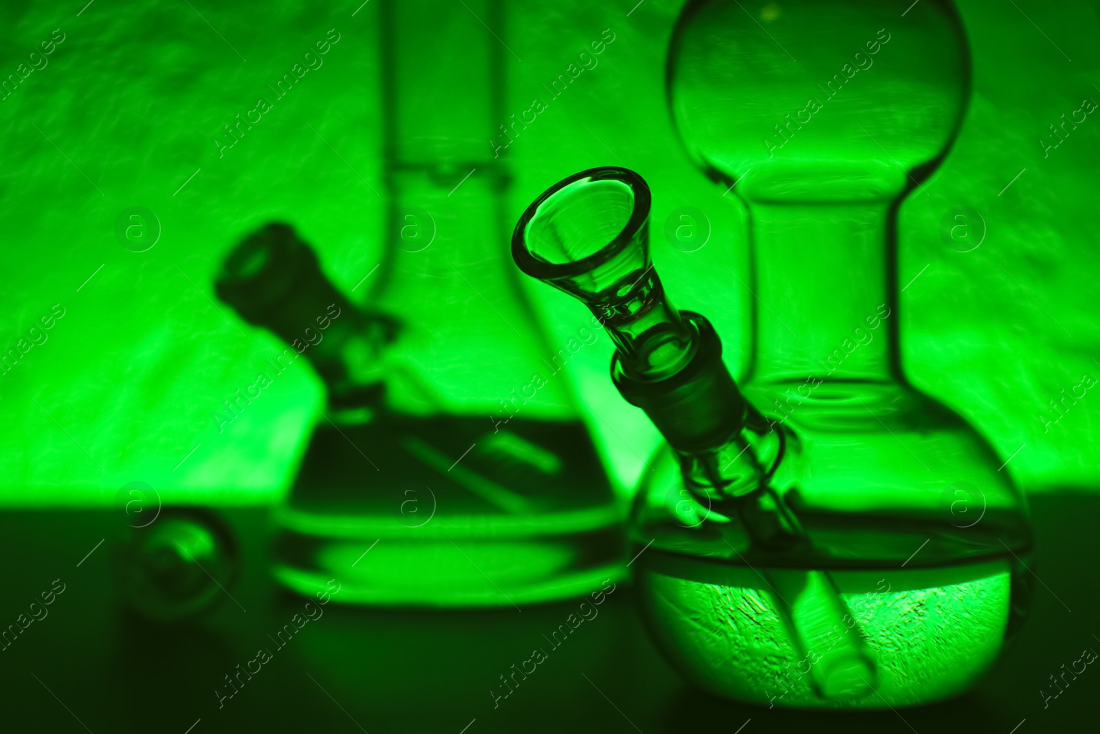 Photo of Closeup view of glass bongs on table, space for text. Smoking device