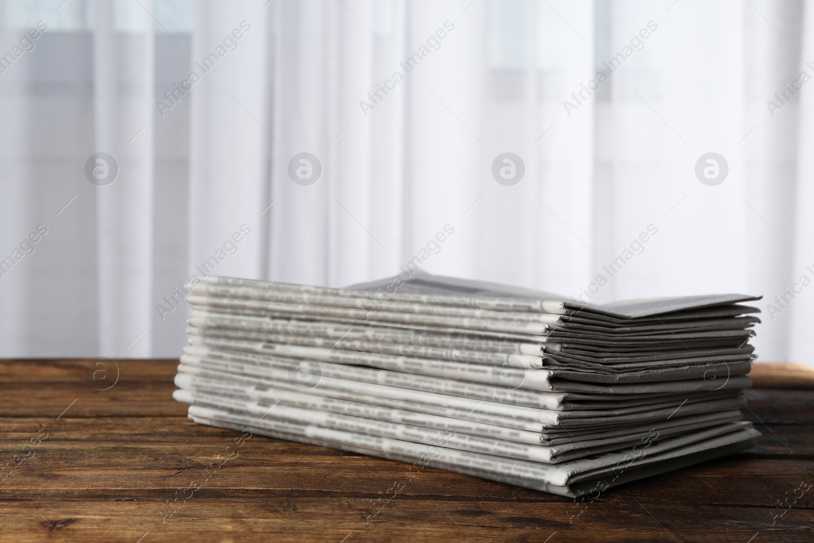 Photo of Stack of newspapers on wooden table. Journalist's work