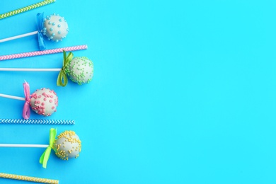 Photo of Tasty cake pops and straws on light blue background, flat lay. Space for text