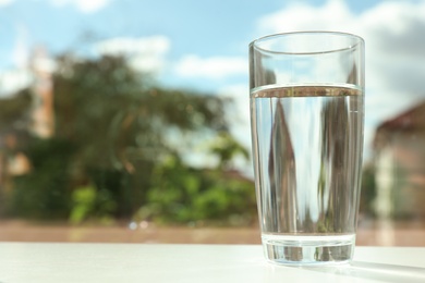 Photo of Glass of fresh water on table outdoors. Space for text