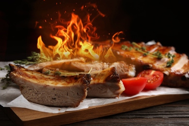 Image of Tasty roasted ribs with flame on wooden table