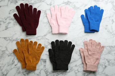 Set of stylish gloves on white marble background, flat lay