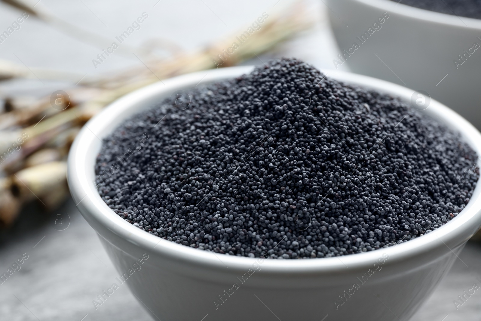 Photo of Poppy seeds in bowl on table, closeup