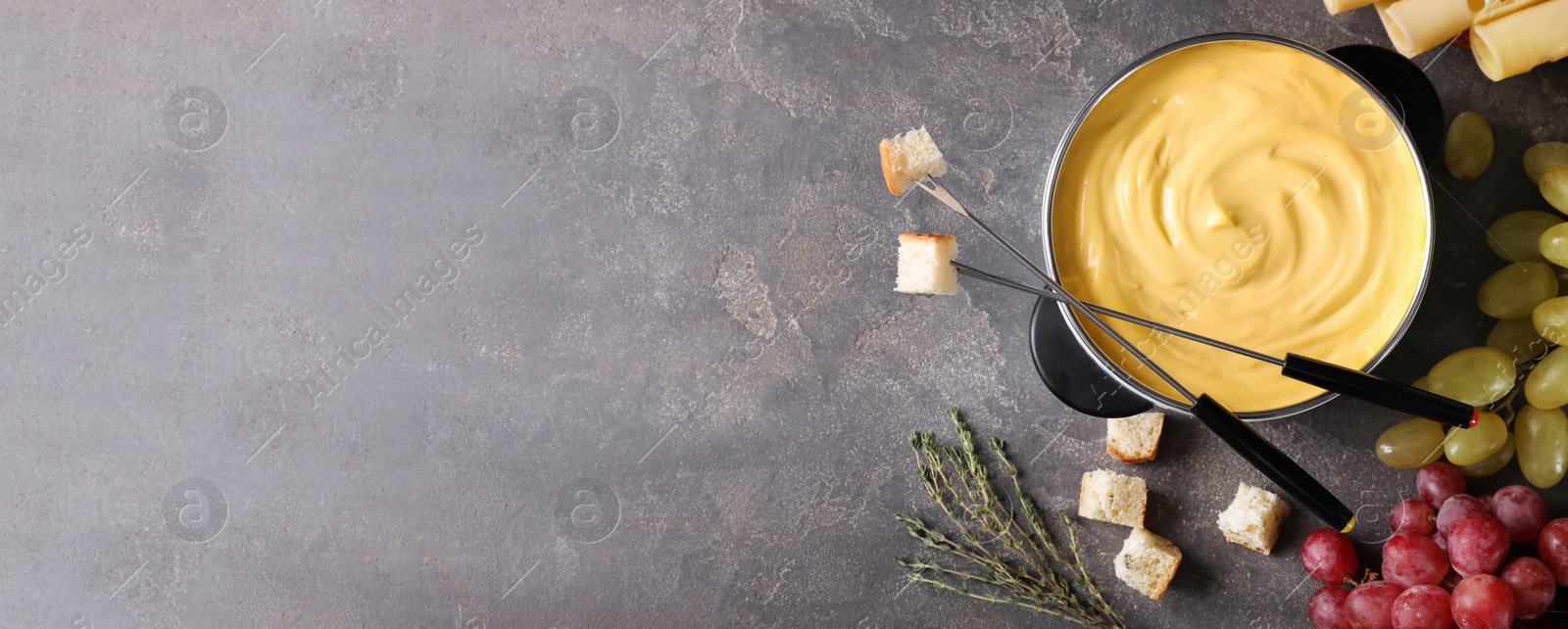 Image of Flat lay composition with pot of delicious cheese fondue on grey table, space for text. Banner design