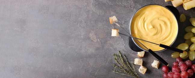 Image of Flat lay composition with pot of delicious cheese fondue on grey table, space for text. Banner design