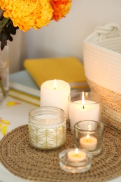Photo of Beautiful burning candles, bag and flowers on table at home
