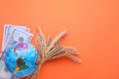Photo of Import and export concept. Globe, ears of wheat and money on orange background, flat lay. Space for text