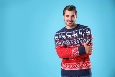 Photo of Portrait of happy young man in Christmas sweater on light blue background. Space for text