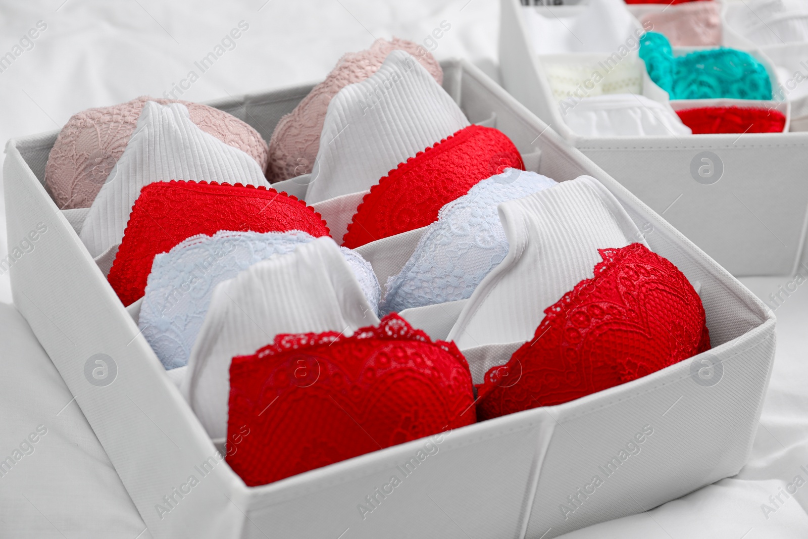 Photo of Organizers with stylish women's underwear on bed, closeup