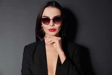 Beautiful woman wearing jacket and sunglasses on black background