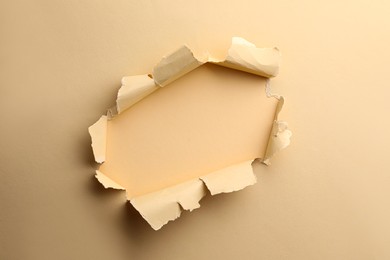 Hole in light beige paper on color background
