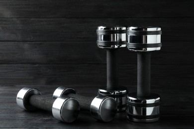 Photo of Set of metal dumbbells on black wooden table