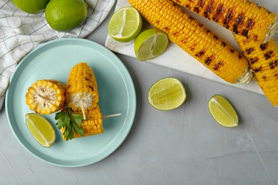 Photo of Flat lay composition of grilled corn cobs on light grey table