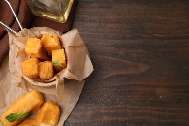 Photo of Tasty fried mozzarella sticks on wooden table, above view. Space for text