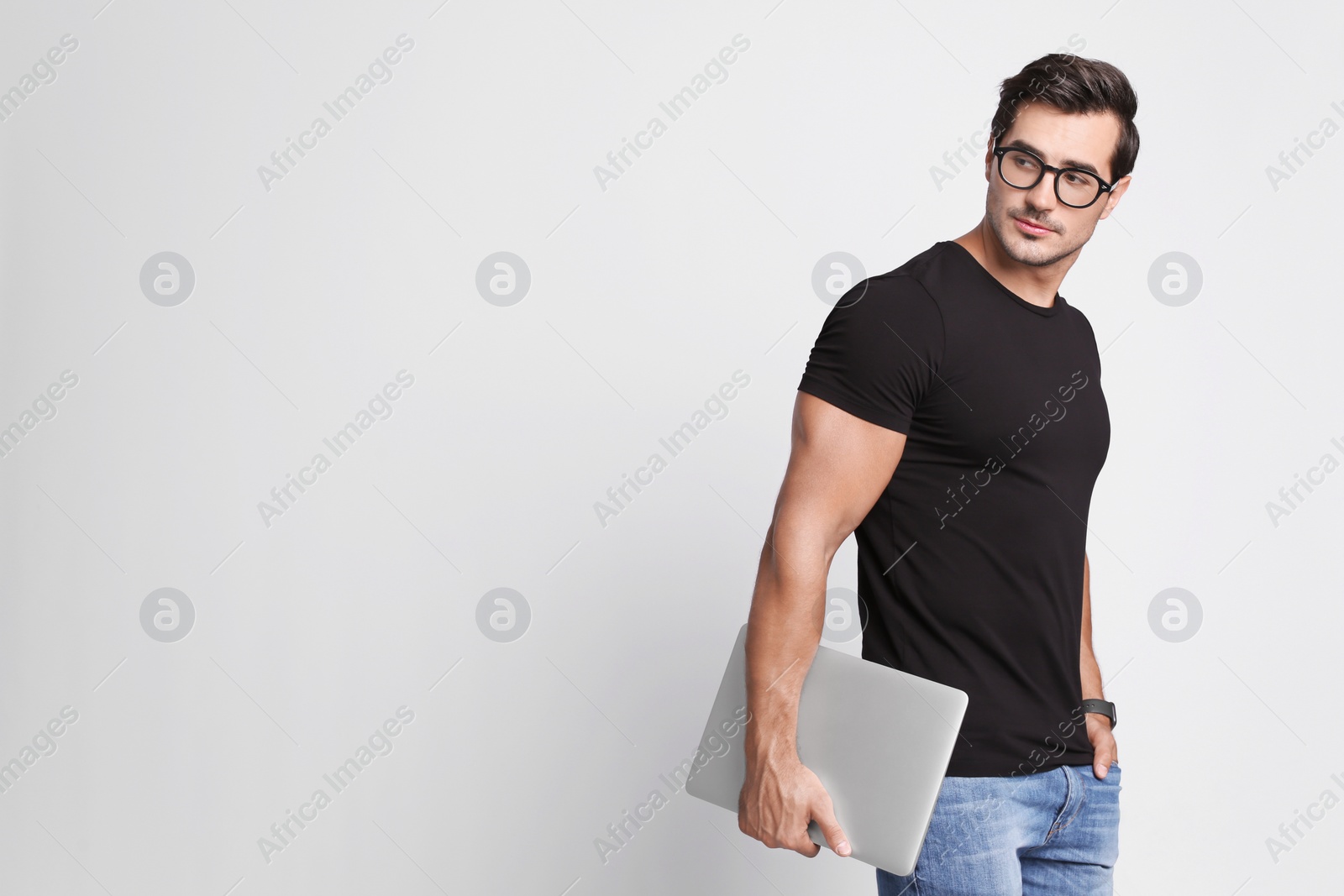 Photo of Handsome young man with laptop on grey background. Space for text