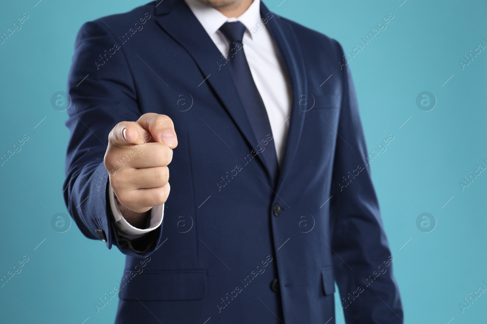 Photo of Businessman touching something on light blue background, closeup. Finger gesture