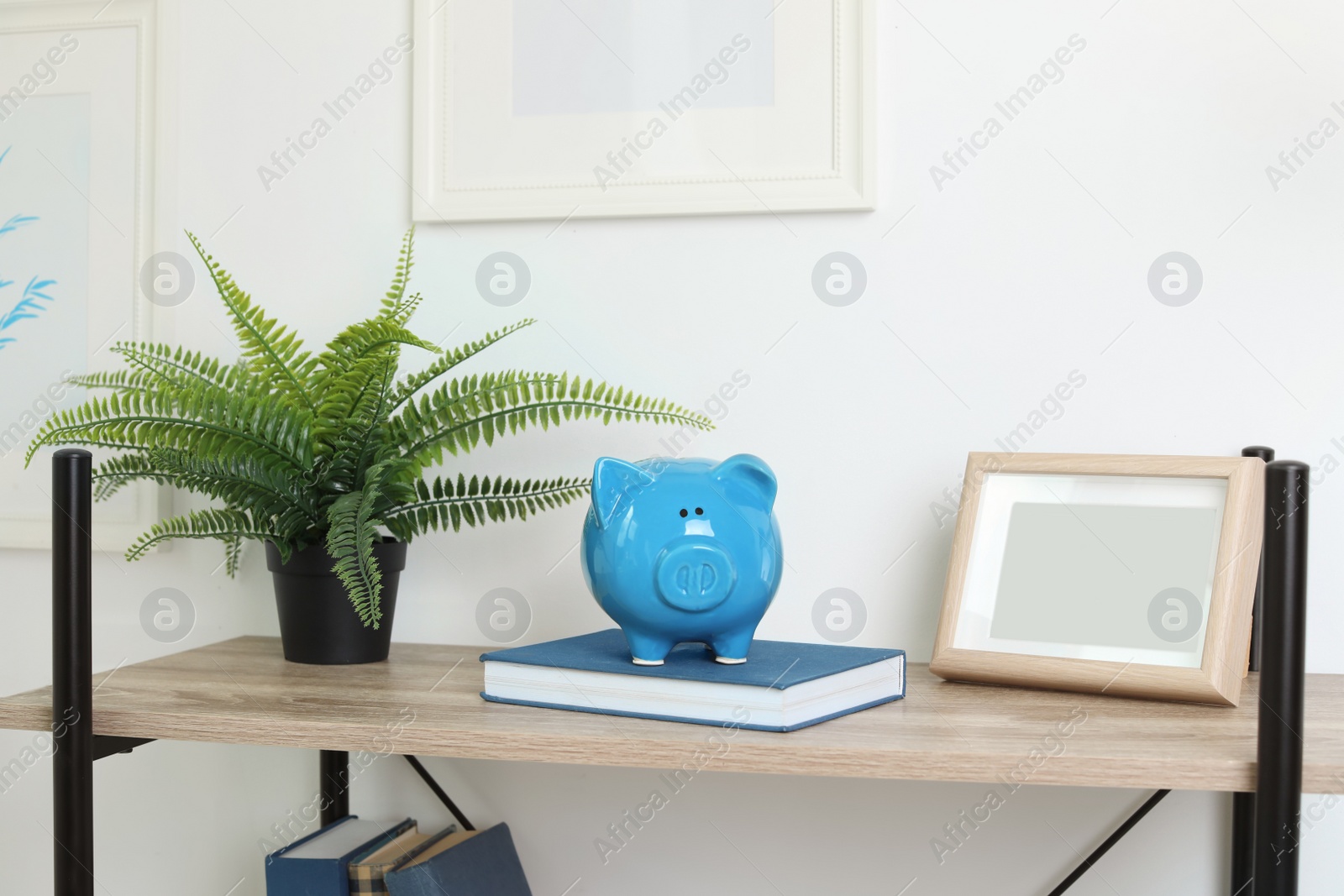 Photo of Shelving unit with decorative interior elements and piggy bank near white wall