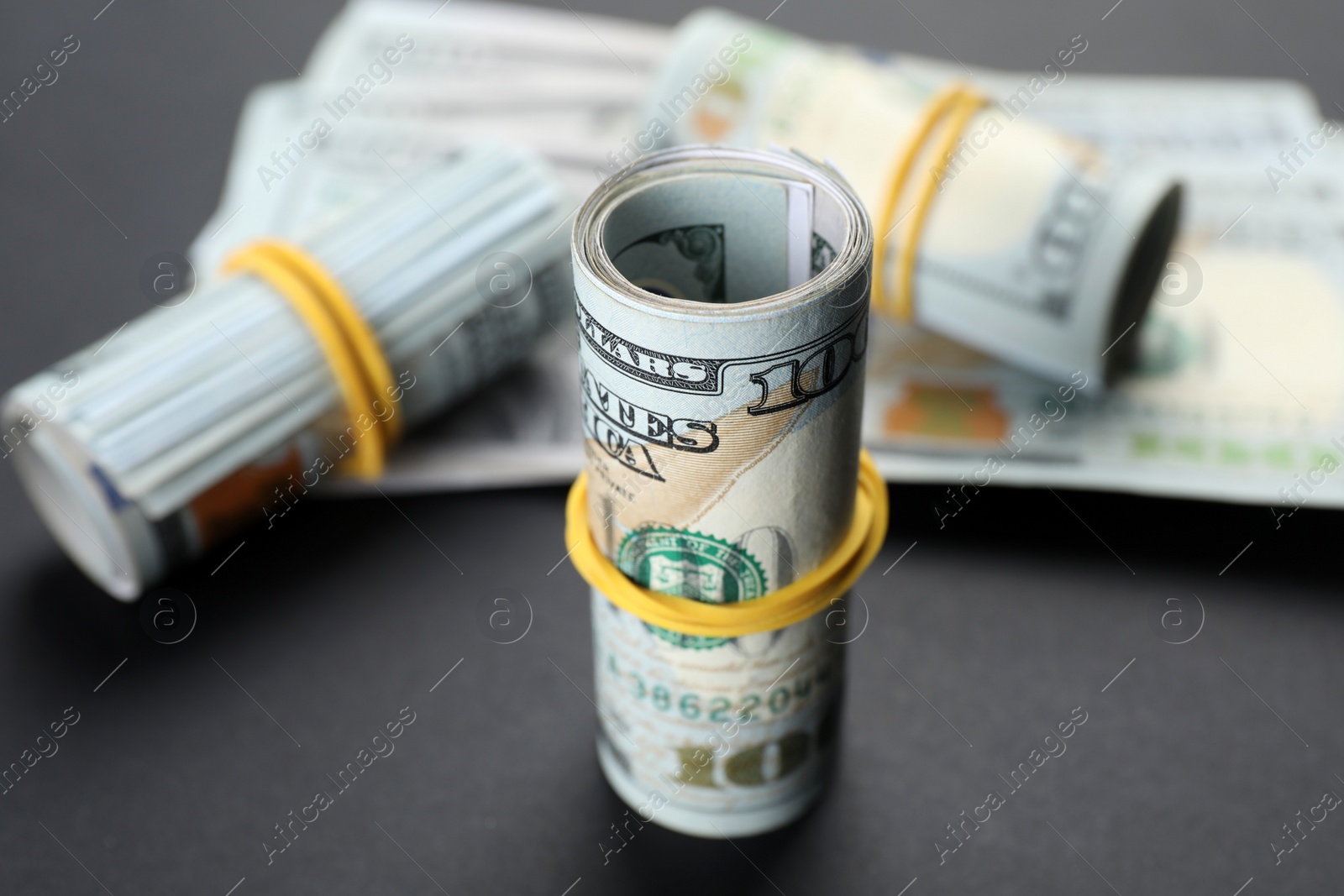 Photo of Rolled dollar banknotes on black background, closeup. American national currency