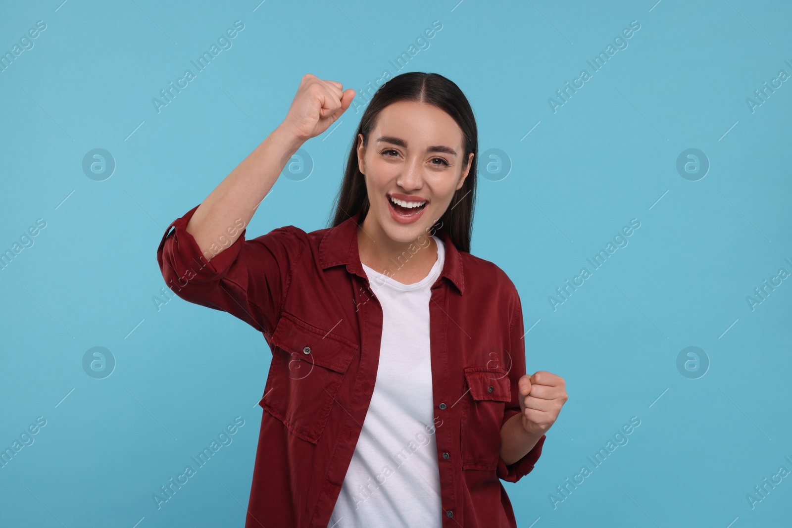 Photo of Happy sports fan celebrating on light blue background