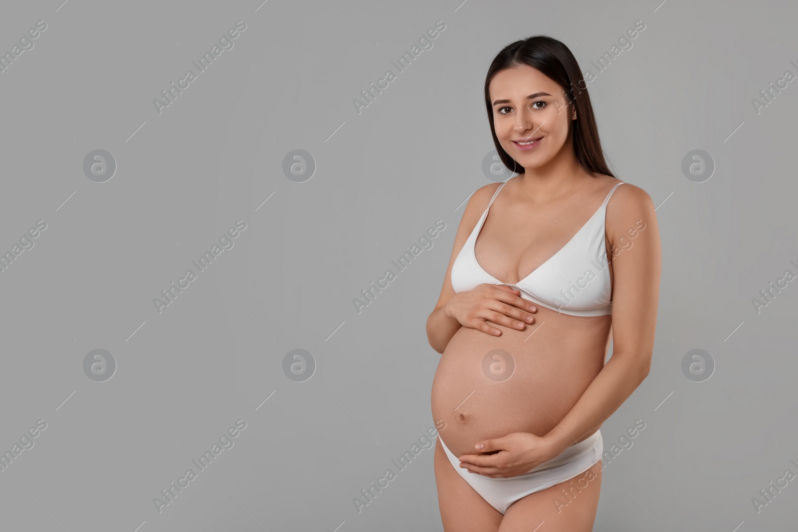 Photo of Beautiful pregnant woman in stylish comfortable underwear on grey background, space for text