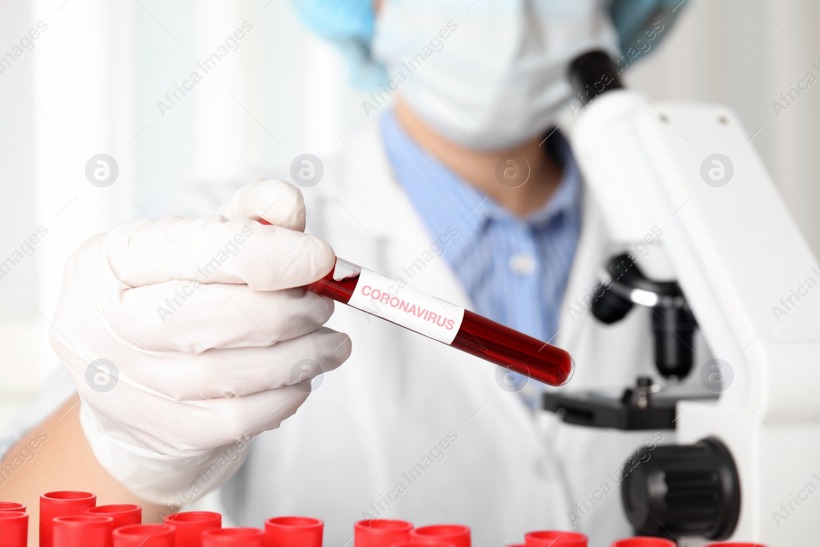 Photo of Scientist holding test tube with blood sample and label CORONA VIRUS in laboratory, closeup