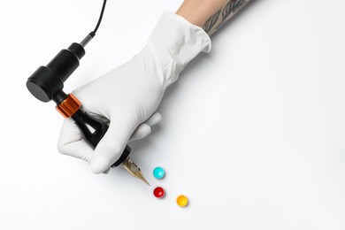 Tattoo artist with professional machine and colorful ink on white background, top view