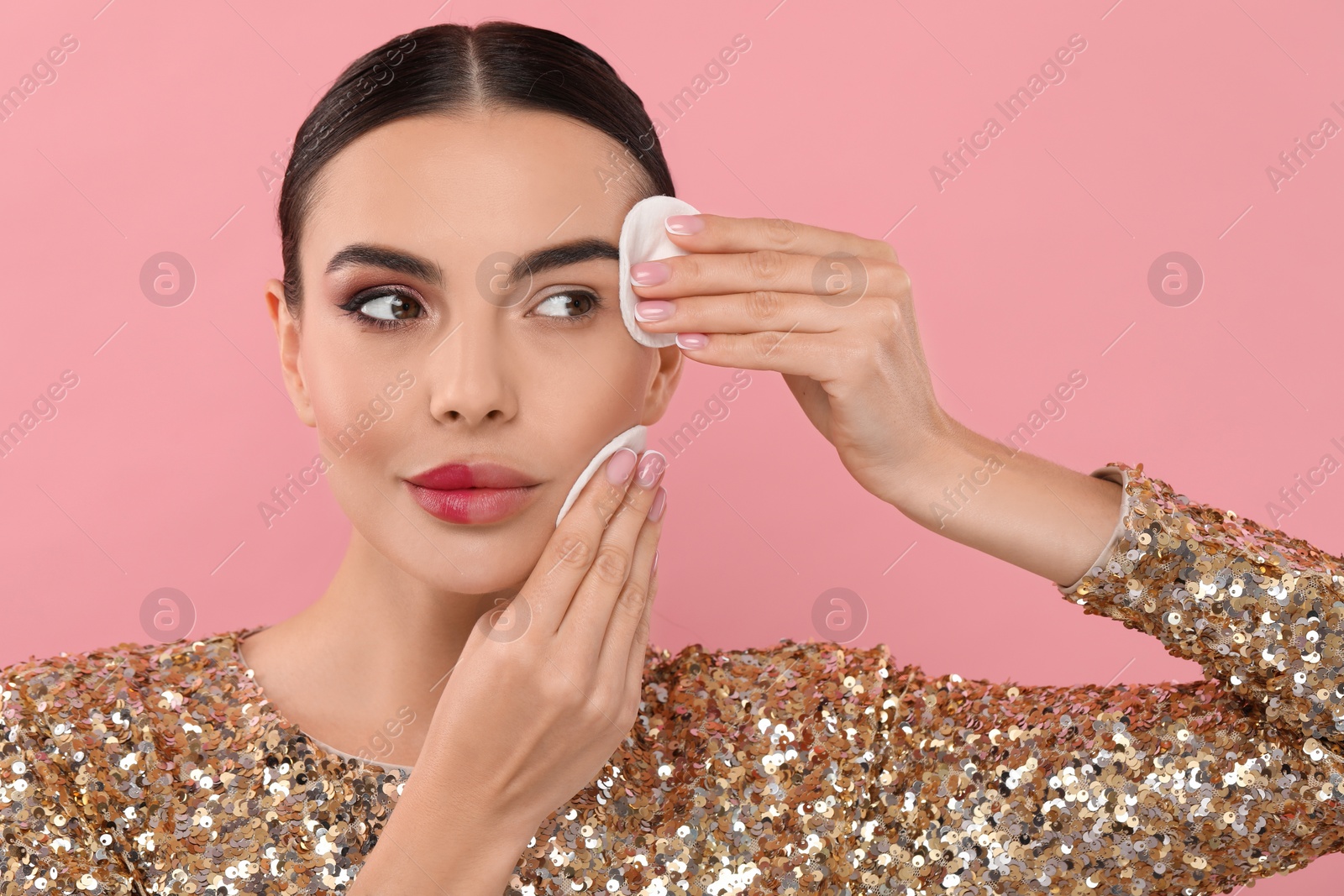 Photo of Beautiful woman removing makeup with cotton pads on pink background