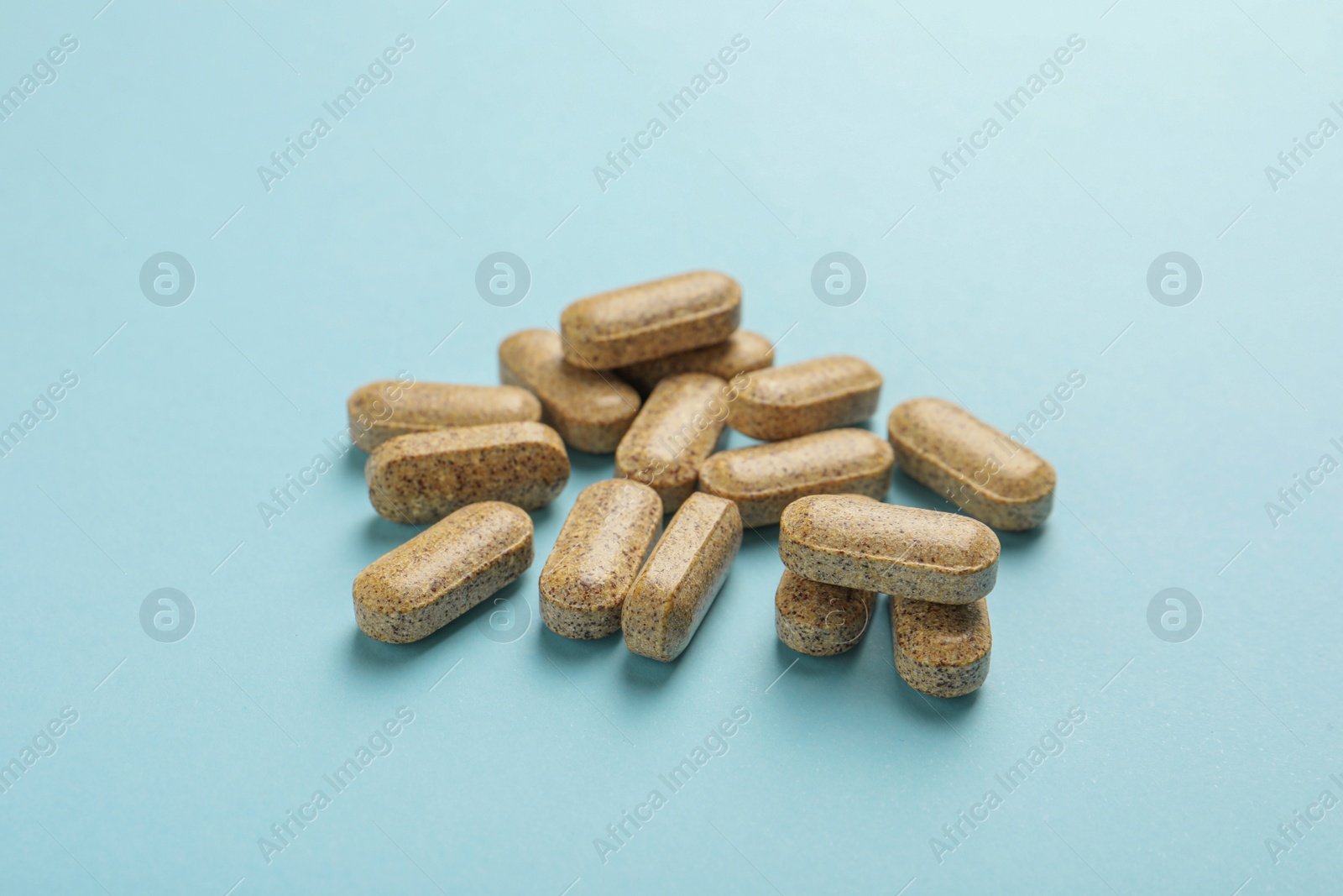 Photo of Dietary supplement pills on light blue background