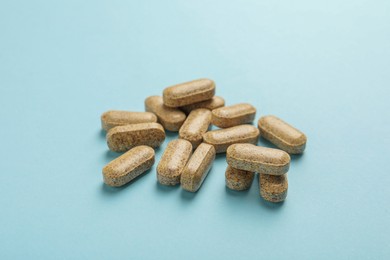 Dietary supplement pills on light blue background