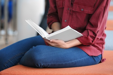 Photo of Young woman reading book in library, closeup