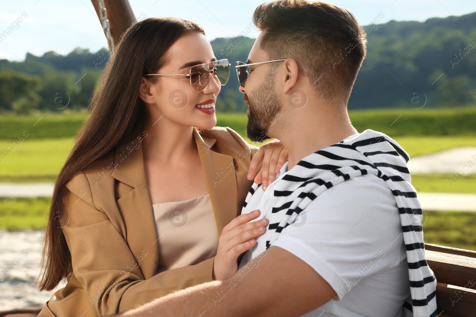 Photo of Romantic date. Beautiful couple spending time together on swing bench outdoors