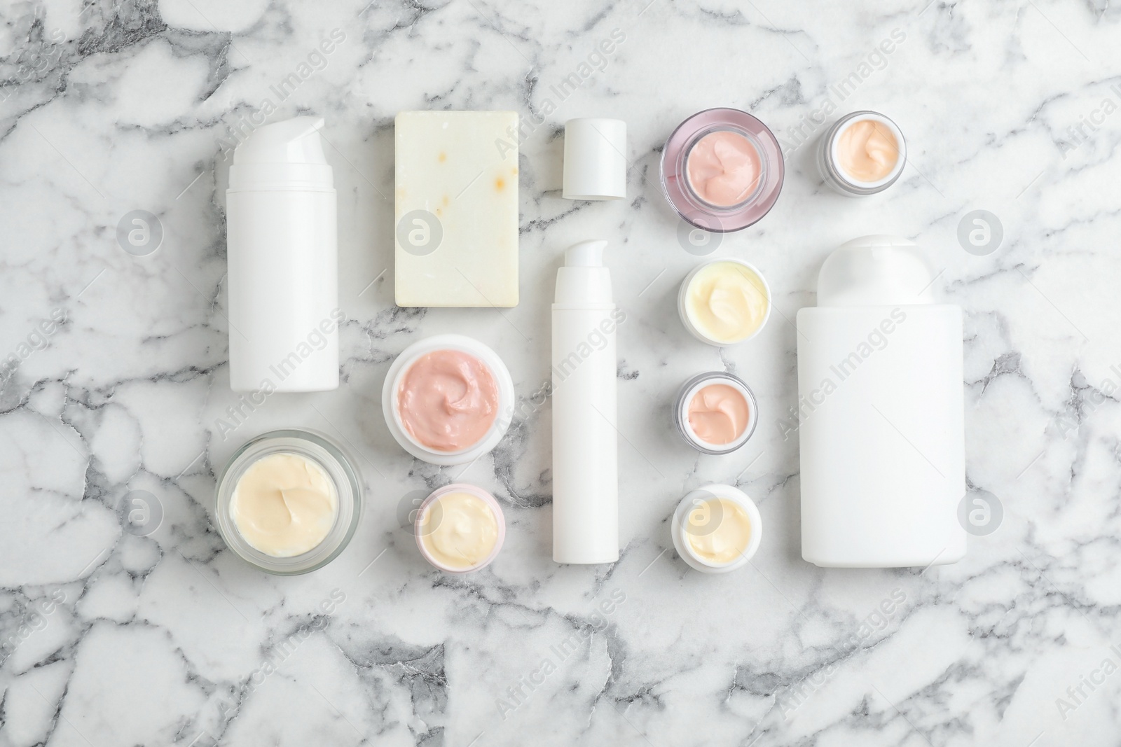 Photo of Flat lay composition with hand cream jars on marble background